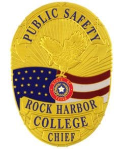 Police badge rock harbor college gold badge a yellow badge with blue text and a bird