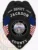 A custom metal badge in black featuring the title "DEPUTY" at the top, along with the name "JACKSON" and "SINCE 1905." The center showcases a circular emblem of the state of Iowa, flanked by decorative blue panels and American flags on either side. Below the emblem, the badge reads "COUNTY IA." The matte black finish gives the badge a sleek and modern appearance, emphasizing its official status and authority in law enforcement.